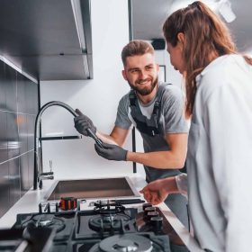 young-professional-plumber-in-grey-uniform-shows-results-of-work-for-housewife-on-the-kitchen-q25w1nopk1bplfeakirhyps008xh221aihxs0o6700 young-professional-plumber-in-grey-uniform-shows-results-of-work-for-housewife-on-the-kitchen-q25w1nopk1bplfeakirhyps008xh221aihxs0o6700